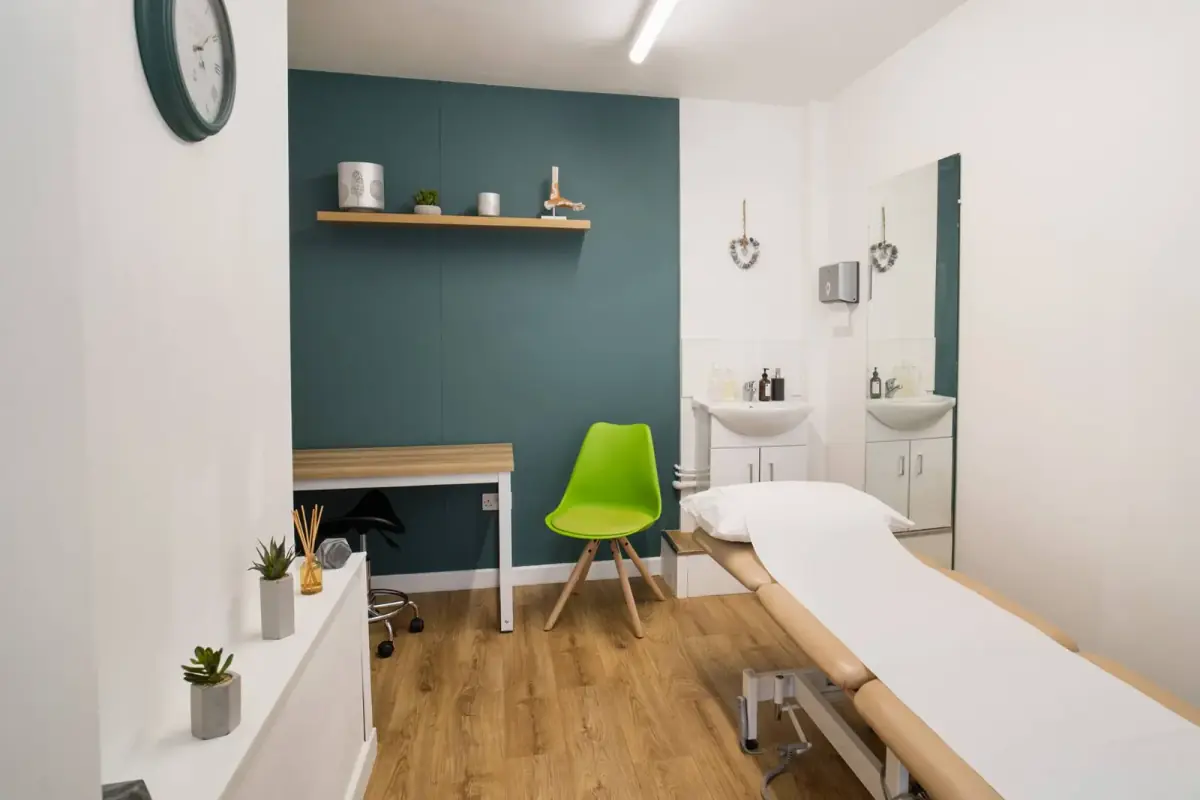 Treatment room at Barefoot Physio Exeter with a treatment couch and teal feature wall