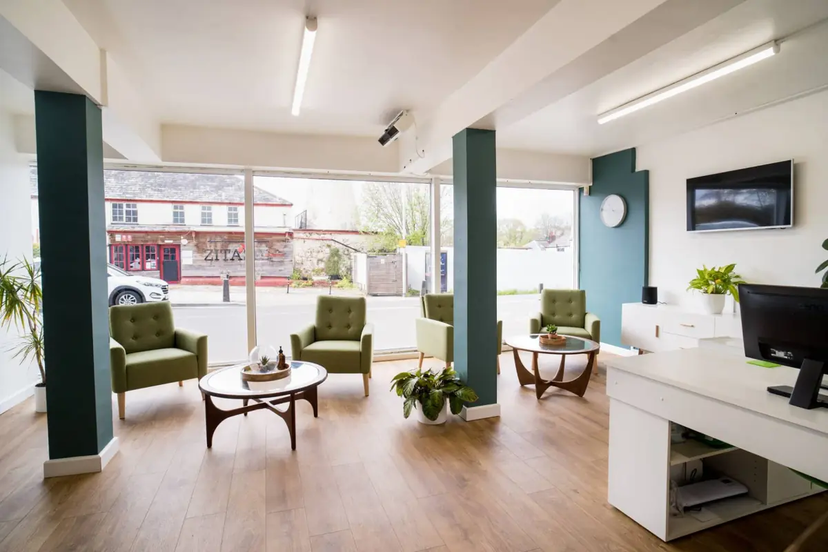 The bright reception and waiting area of the Exeter clinic, with green armchairs by the street window